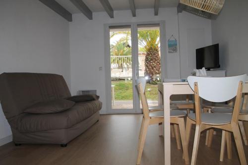 een woonkamer met een bank en een tafel en stoelen bij Anglet : Duplex dans résidence avec piscine in Anglet