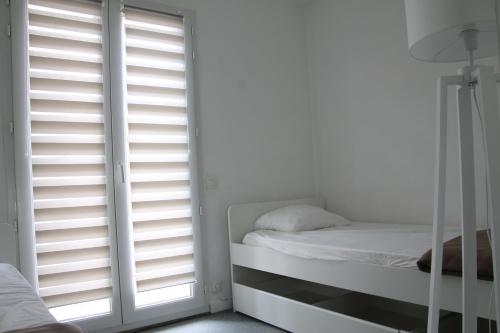 a bedroom with white shuttered windows and a bed at Anglet : Duplex dans résidence avec piscine in Anglet