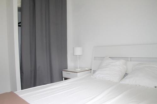 a bed with white sheets and a lamp on a night stand at Anglet : Duplex dans résidence avec piscine in Anglet