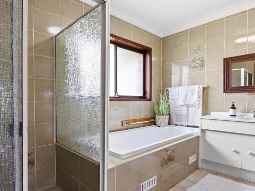 a bathroom with a shower and a tub and a sink at Sea Bird in Culburra Beach