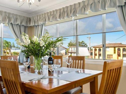 a dining room with a table with a vase of flowers at Sea Gem in Callala Beach