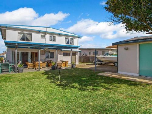 a white house with a blue roof and a yard at Sea Gem in Callala Beach