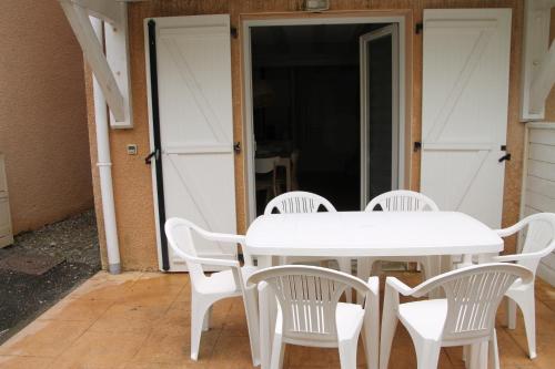 una mesa blanca y sillas frente a una puerta en Anglet : Duplex dans résidence avec piscine, en Anglet