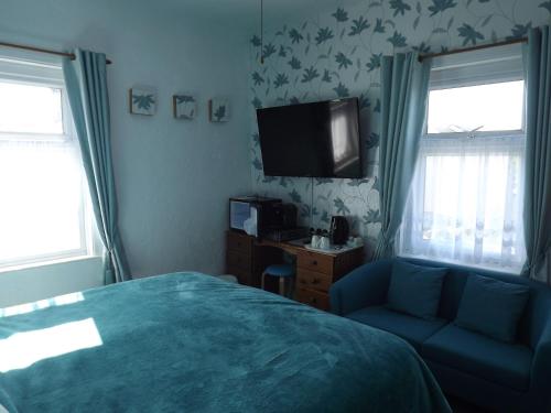 1 dormitorio con 1 cama, TV y sofá en The Chequers, en Great Yarmouth