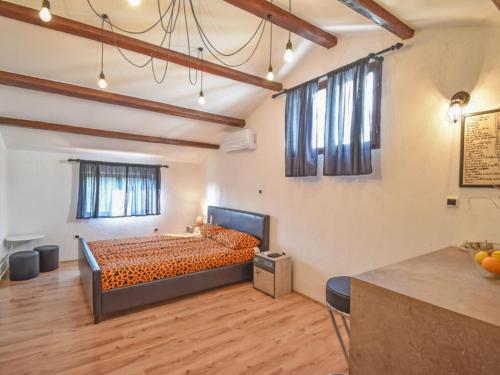 a bedroom with a bed with orange sheets and wooden floors at Studios Barre with Jacuzzi in Rovinj