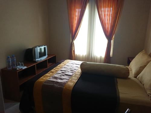 a bedroom with a bed and a tv and a window at Villagio Hotel in Pameungpeuk