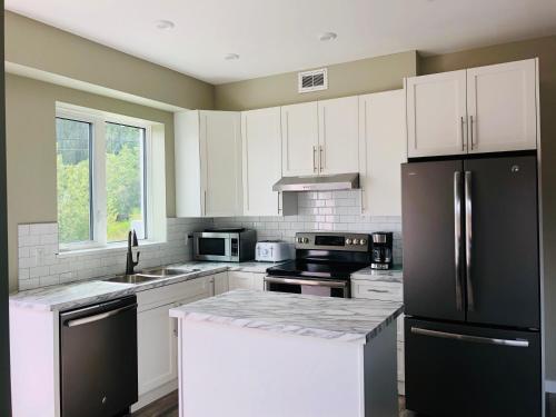 a kitchen with white cabinets and a black refrigerator at Downtown Whitehorse Deluxe 2 Bedroom Condo in Whitehorse
