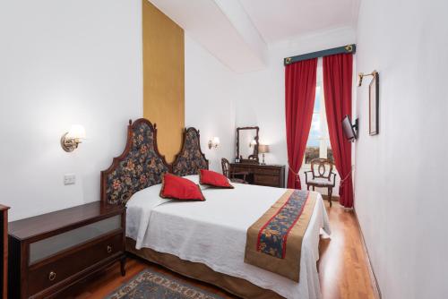 a bedroom with a bed and a desk and a window at Hotel Castille in Valletta