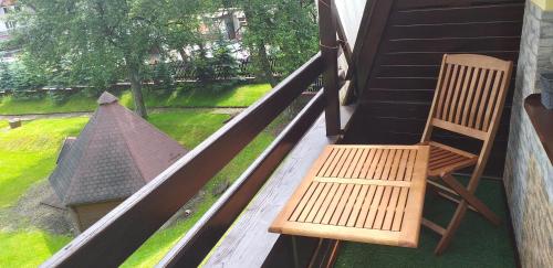uma cadeira de madeira sentada num alpendre com uma janela em Mieszkanie u Dominiki INPIW01 em Piwniczna