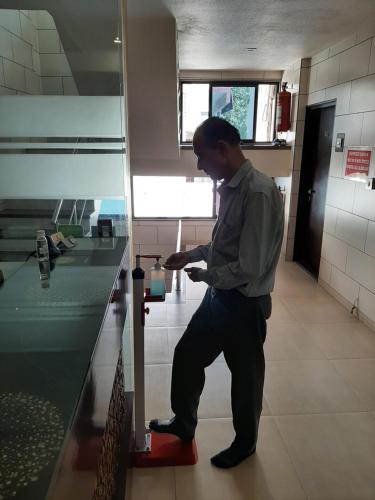 a man standing in a kitchen looking at his cell phone at Hotel Good Night in Ahmedabad