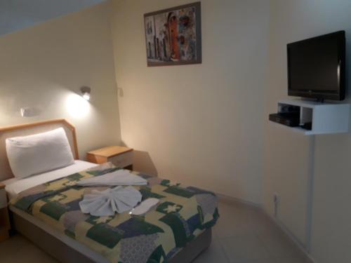 a small bedroom with a bed and a flat screen tv at Hotel NilSu in Oludeniz