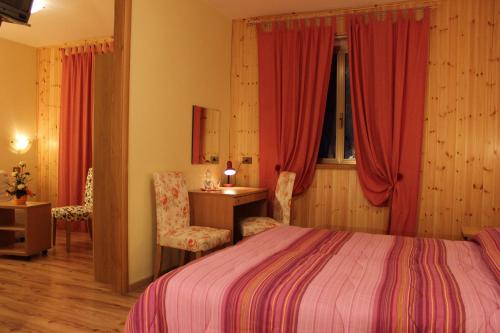 una camera con letto, scrivania e sedia di Albergo Ristorante Montecucco da Tobia a Sigillo