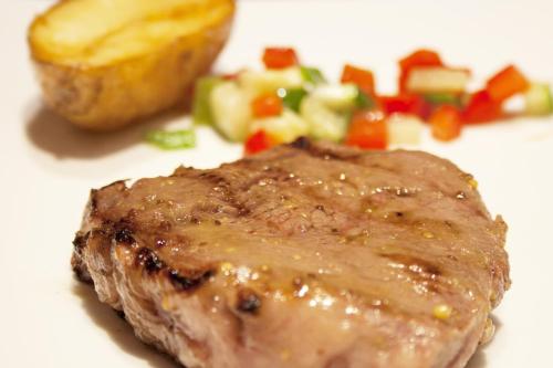 a piece of meat on a white plate with vegetables at Hotel Centro Los Braseros in Burgos