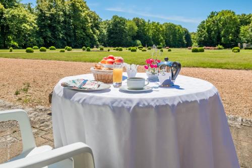 a white table with a basket of fruit and drinks at Château De Denonville in Denonville