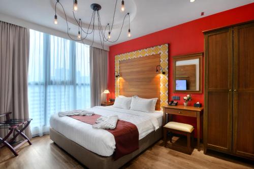 a bedroom with a large bed with a red wall at The Granite Luxury Hotel Penang in George Town