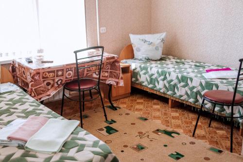 アフトゥビンスクにあるHotel Almazのベッド2台、テーブル、椅子が備わる客室です。