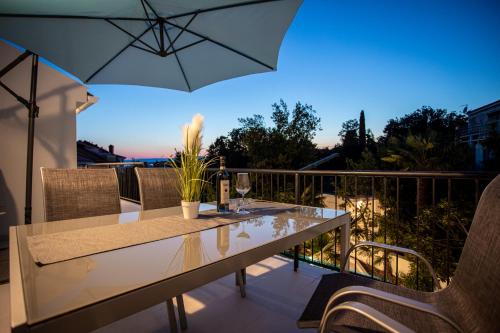 d'une table et de chaises sur un balcon avec un parasol dans l'établissement Apartments San Leopoldo, à Crikvenica