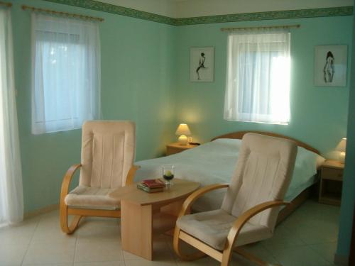 a bedroom with a bed and two chairs and a table at Madách Apartman in Hévíz