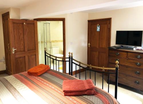 a bedroom with a bed with a television and a dresser at The Old Mill Bed and Breakfast in Bere Regis