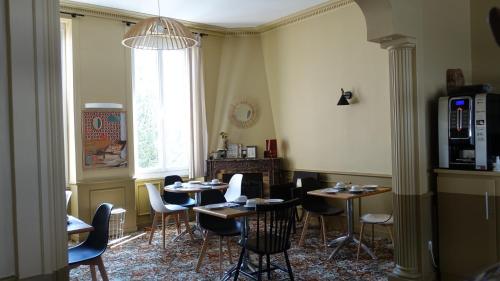 a dining room with tables and chairs and a window at Cit'Hotel Les Alizes in Dinard