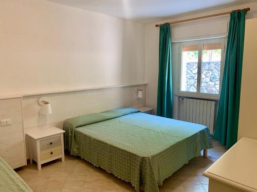 a bedroom with a bed and a window with green curtains at Appartamenti Tallinucci in Lacona
