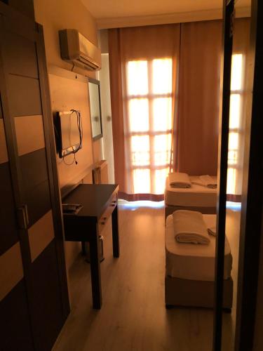 a small room with two beds and a desk and a window at Sun Hotel in Çeşme
