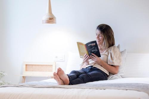 a woman sitting on a bed reading a book at Getaria Apartamentuak - Balentziaga in Getaria