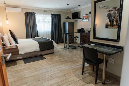 a bedroom with a bed and a desk and a table at Casa Leitao Lodge in Phalaborwa