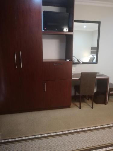 a room with a desk and a cabinet with a television at Belmont Guesthouse in Bloemfontein