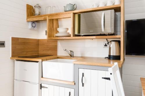 a kitchen with white cabinets and a microwave at Weedingshall Lodges in Falkirk