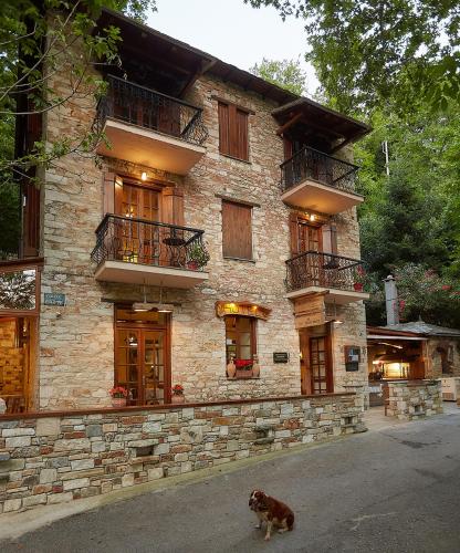 a dog sitting in front of a stone building at Palios Stathmos in Miléai