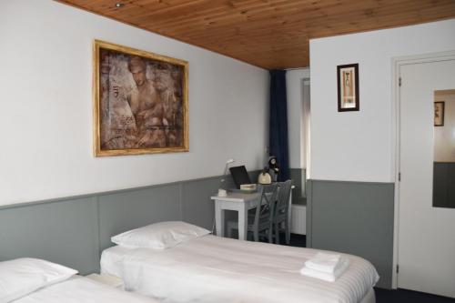 two beds in a room with a desk and a painting on the wall at Hotel Verhoeven in Uden