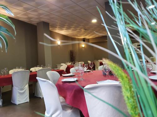a dining room with a red table and white chairs at Hotel Valdemoro in Valdemoro