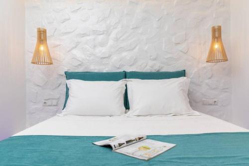 Una cama con dos almohadas y una revista. en Arktos Luxury Apartment, en Naxos Chora