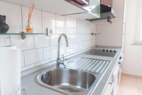 eine Spüle aus Edelstahl in einer Küche mit weißen Fliesen in der Unterkunft Studio ENIG in Izola