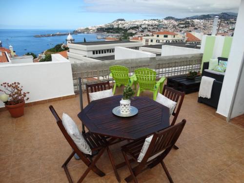 una mesa y sillas en un balcón con vistas al océano en Barreirinha Funcho House, en Funchal