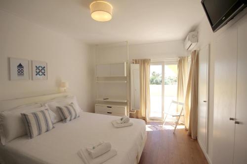een slaapkamer met een wit bed met handdoeken erop bij Villa Rosa A by amcf in Portimão