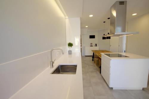 een witte keuken met een wastafel en een tafel bij Villa Rosa A by amcf in Portimão