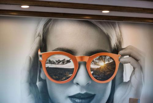 a woman wearing orange glasses in front of a picture at La Quinta Inn & Suites by Wyndham Wisconsin Dells- Lake Delton in Wisconsin Dells