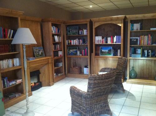 a library with three chairs and book shelves with books at Logis Hôtel Louise de Savoie in Blois