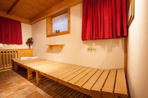 a room with a wooden bench and red curtains at Haus Steinbock in Neustift im Stubaital