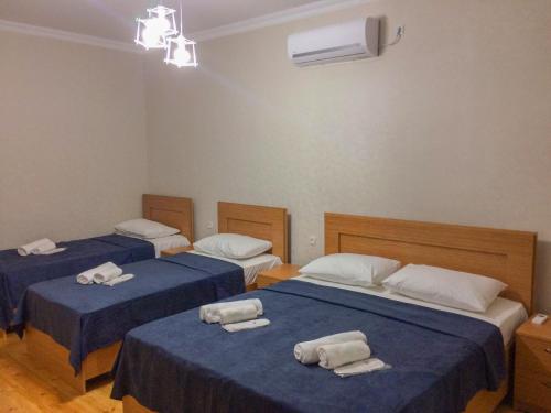 three beds in a room with blue sheets and towels on them at Guest House Maradona in Sighnaghi