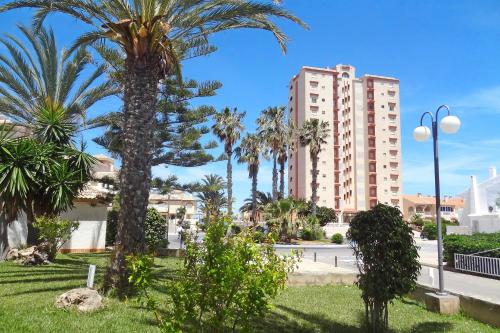 eine Palme in einem Park mit einem Gebäude in der Unterkunft Torre Riviera in La Manga del Mar Menor