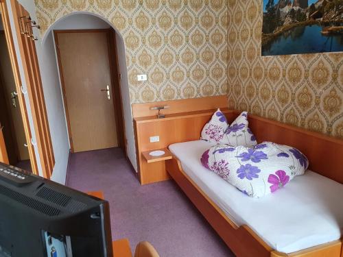 1 dormitorio pequeño con 1 cama y TV en Gasthof Mooserwirt - Passeiertal, en Moso in Passiria