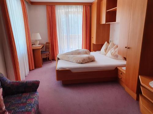 Habitación pequeña con cama y silla en Gasthof Mooserwirt - Passeiertal, en Moso in Passiria
