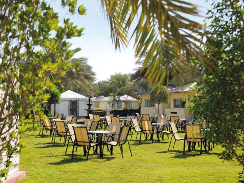 a group of tables and chairs in the grass at Montrose - A Mayfair Collection Hotel in Kuwait