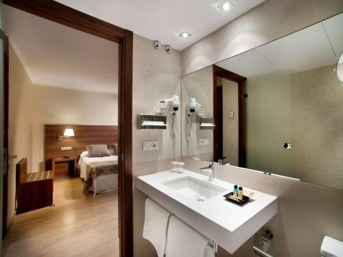 1 dormitorio y baño con lavabo y espejo. en Ibis Styles Figueres Ronda, en Figueres