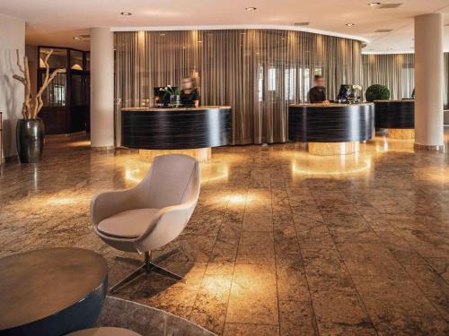 eine Lobby mit einem Wartebereich mit einem Stuhl in der Unterkunft Mövenpick Hotel Lausanne in Lausanne