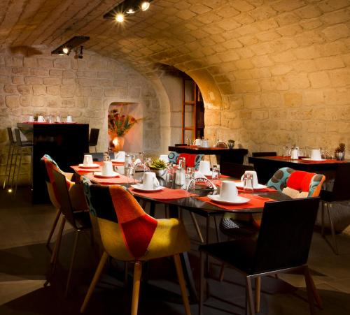 un restaurant avec des tables et des chaises dans une salle en pierre dans l'établissement Hôtel Elixir, à Paris
