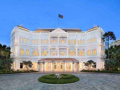 a large white building with a flag on top of it at Raffles Singapore in Singapore